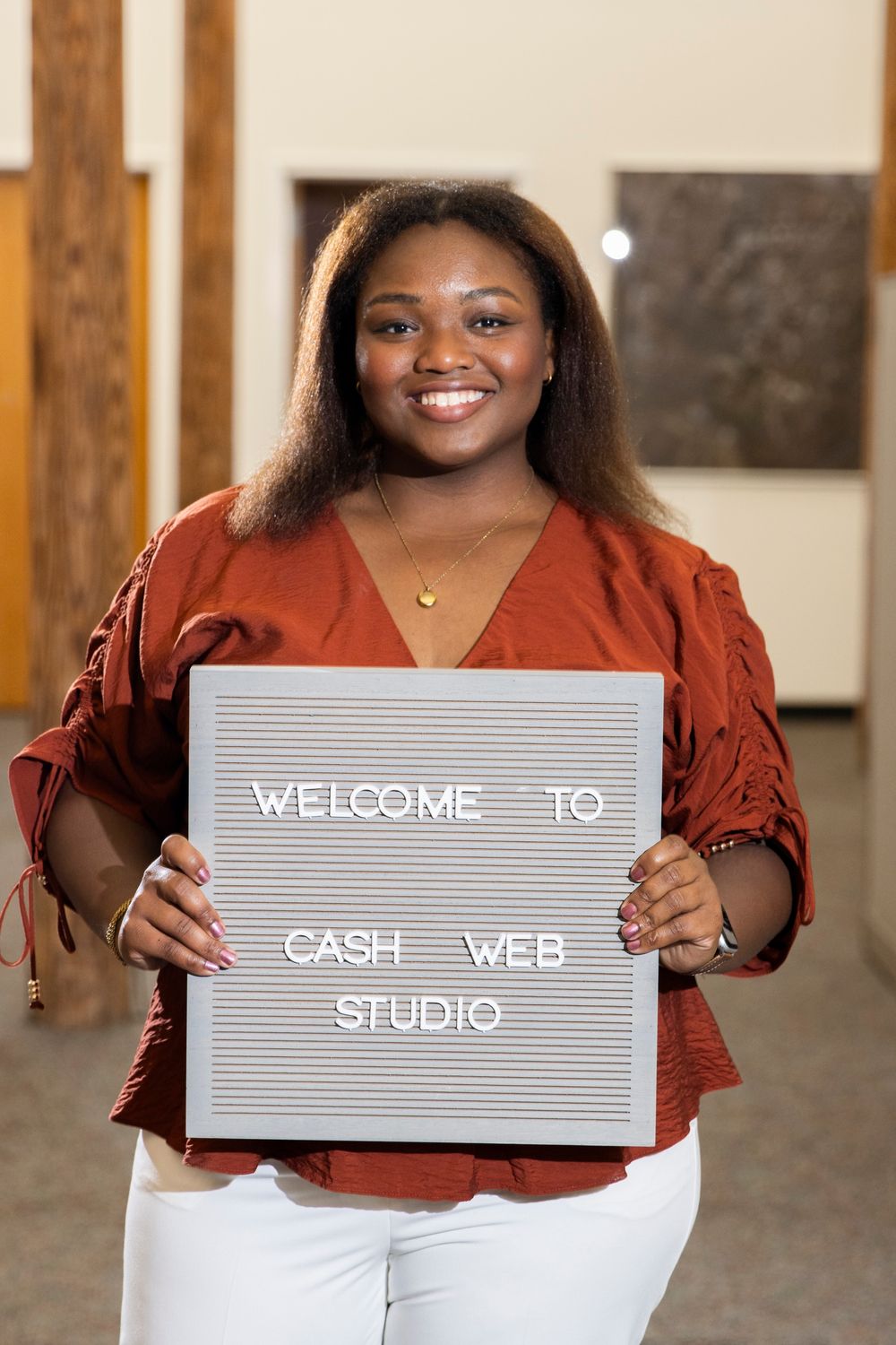 Camille Cash, founder of Cash Web Studio, smiling and holding a letter board that reads Welcome to Cash Web Studio